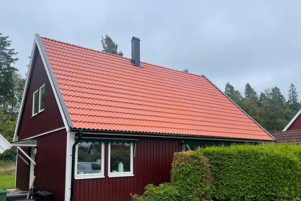 Nybyggt fritidshus vid sjön med altan och svensk flagga