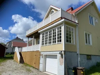 Gult hus med inbyggd balkong och garage