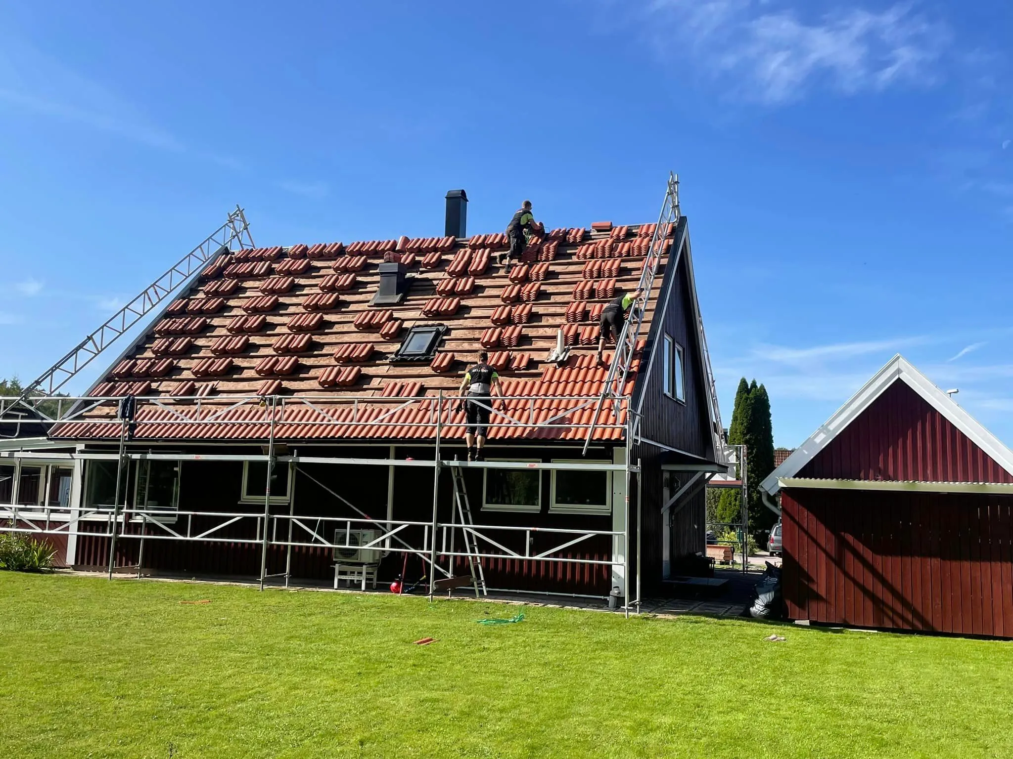 Takbyte med nytt tegel på falurött hus